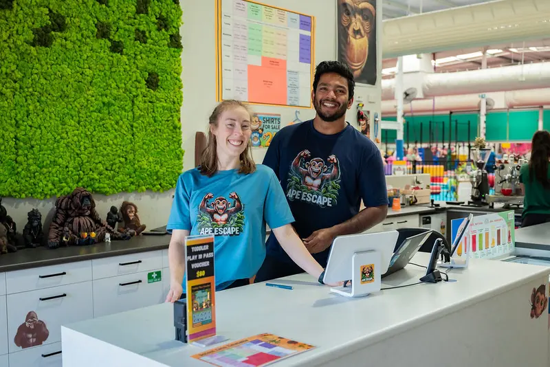 Two Ape Escape staff in branded t-shirts smiling behind the front desk